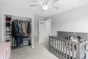 Carpeted bedroom with ceiling fan and a closet