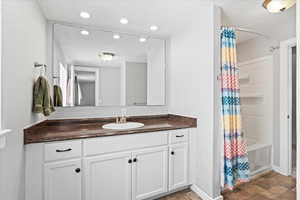Bathroom with recessed lighting, baseboards, shower / bath combination with curtain, and vanity