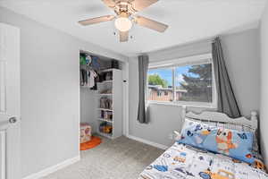 Carpeted bedroom with a ceiling fan, baseboards, and a closet