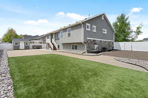 Back of house featuring stone siding, a storage shed, stucco siding, and a fenced backyard.