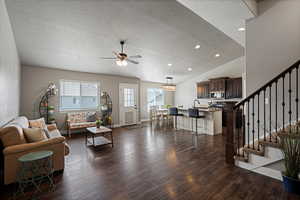 Living room featuring stairway, a ceiling fan, dark wood-style floors, and a textured ceiling