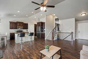 Living room featuring dark wood-style flooring, baseboards, ceiling fan, a textured ceiling, and vaulted ceiling