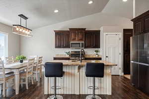 Kitchen with a sink, dark wood finished floors, appliances with stainless steel finishes, and vaulted ceiling