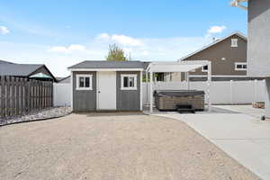 Backyard outbuilding with a hot tub, an adjustable gazebo and patio campfire ring.