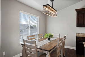 Dining area with baseboards, dark wood-style floors, and an inviting chandelier