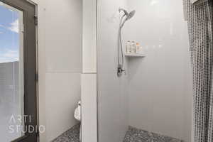 Pool Bathroom with a tile shower, toilet, and tile walls