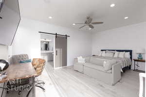 Primary Bedroom featuring recessed lighting, a barn door, light wood-style flooring, and ensuite bathroom