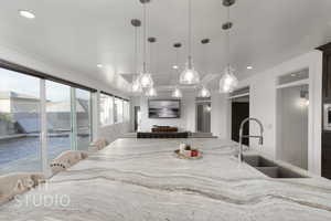 Kitchen featuring recessed lighting, a sink, pendant lighting, and light stone countertops