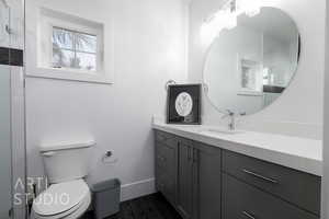 Ensuite Full bath with vanity, wood look tile floors, a shower, toilet, and baseboards