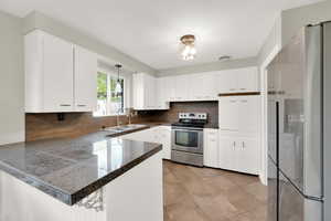 Kitchen with a sink, stainless steel appliances, decorative light fixtures, tile countertops, and decorative backsplash