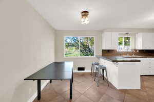 Kitchen with white cabinetry, a breakfast bar area, and dark countertops