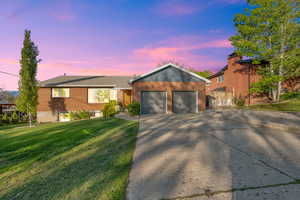 Ranch-style house featuring a lawn, fence, driveway, and brick siding