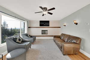 Living room featuring baseboards, a ceiling fan, wood finished floors, and a fireplace