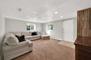 Living room featuring visible vents, recessed lighting, a textured ceiling, and light carpet