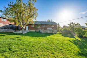 Rear view of property with brick siding, a fenced backyard, and a yard