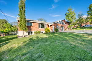 Ranch-style home with fence, an attached garage, brick siding, a front yard, and driveway