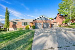 Single story home with fence, a front yard, brick siding, an attached garage, and driveway