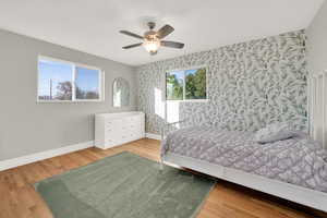 Bedroom with baseboards, an accent wall, and wallpapered walls