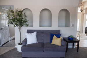 Tiled living area featuring carpet floors, baseboards, and an inviting chandelier