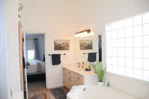 Full bathroom featuring a healthy amount of sunlight, vanity, wood finished floors, and connected bathroom