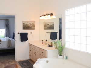 Ensuite bathroom featuring vanity, wood finished floors, baseboards, a bath, and ensuite bath