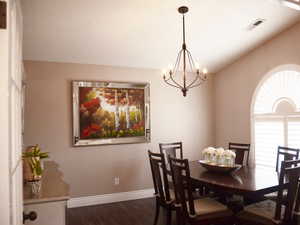 Dining area with visible vents, dark wood-style flooring, baseboards, a chandelier, and vaulted ceiling