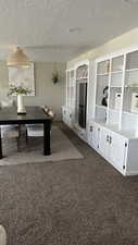 Interior space featuring dark colored carpet and a textured ceiling