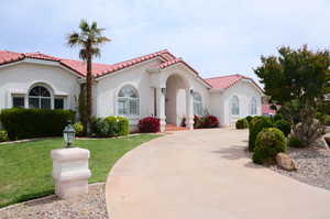 Mediterranean / spanish-style home with stucco siding, a tile roof, and circular drive