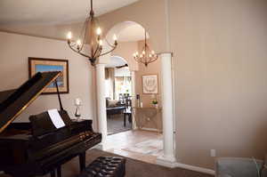 Hallway featuring an inviting chandelier, arched walkways, carpet floors, and lofted ceiling