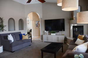 Living area featuring baseboards, carpet flooring, a glass covered fireplace, and ceiling fan