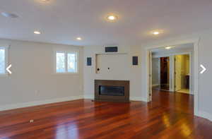 Unfurnished living room featuring a glass covered fireplace, wood-type flooring, and a healthy amount of sunlight