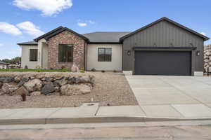 View of front facade featuring concrete driveway, brick siding, roof with shingles, and a garage