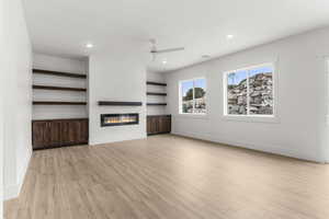 Unfurnished living room with a glass covered fireplace, baseboards, recessed lighting, a ceiling fan, and light wood finished floors