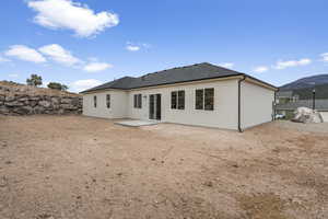 Back of house with a shingled roof, a patio, stucco siding, and a mountain view