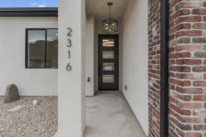 View of exterior entry featuring brick siding and stucco siding