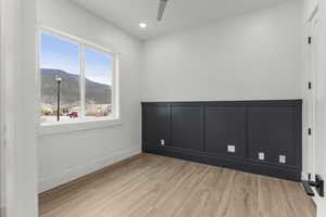 Empty room featuring a ceiling fan, wood finished floors, baseboards, a mountain view, and recessed lighting