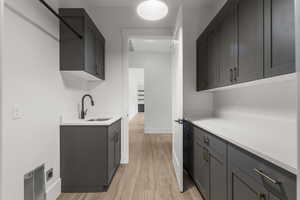 Kitchen with light countertops, baseboards, a sink, and light wood-type flooring