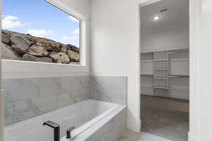 Full bath featuring visible vents, a walk in closet, and a garden tub