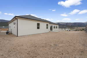 Back of property featuring central air condition unit, a mountain view, stucco siding, and a patio area