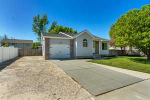 Single story home featuring a garage, brick siding, fence, a front lawn, and concrete driveway
