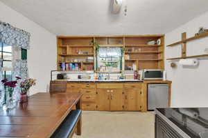 Kitchen featuring tile counters, open shelves, a sink, and stainless steel appliances