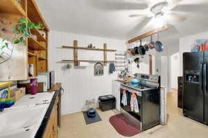 Kitchen with stainless steel range with electric cooktop, open shelves, arched walkways, a ceiling fan, and black fridge with ice dispenser