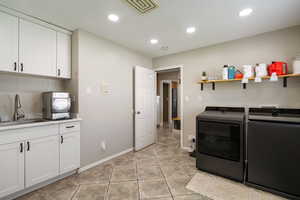 Washroom featuring washing machine and clothes dryer, recessed lighting, a sink, and cabinet space