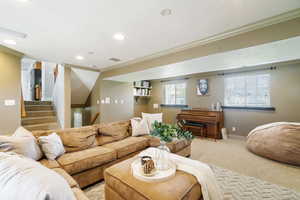 Living area with a textured ceiling, baseboards, ornamental molding, light carpet, and recessed lighting