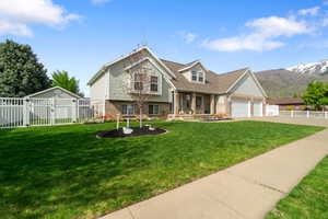 Split level home featuring fence, a gate, a front lawn, and brick siding