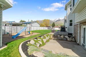 View of yard featuring a patio, a fenced backyard, a playground, and a mountain view