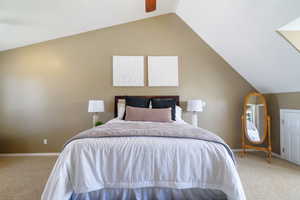 Carpeted bedroom with a ceiling fan, baseboards, and vaulted ceiling