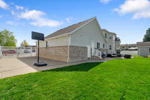 View of property exterior featuring a lawn, a residential view, brick siding, fence, and a patio