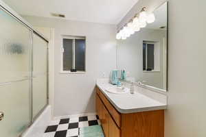 Bathroom featuring tile patterned floors, vanity, shower / bath combination with glass door, and visible vents