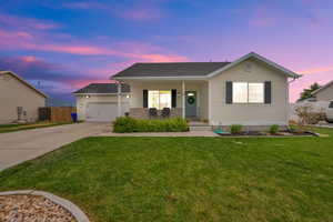 Ranch-style house featuring covered porch, a lawn, a garage, fence, and concrete driveway